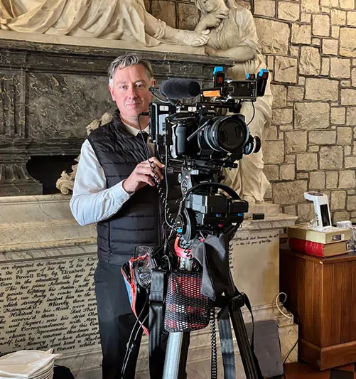 Camera operator with a tripod-mounted video camera and microphone